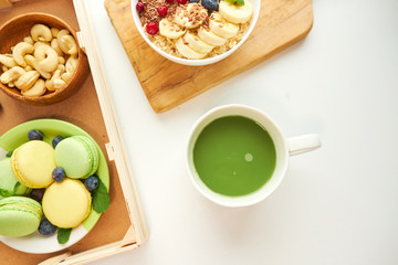 matcha green tea, breakfast top view white background. oatmeal with berries, toasts on a wooden tray, nuts, coffee