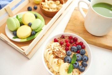 matcha green tea, breakfast top view white background. oatmeal with berries, toasts on a wooden tray, nuts, coffee