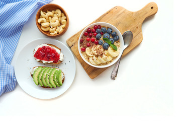 breakfast top view isolate white background. oatmeal with berries, toasts on a wooden tray, nuts, coffee