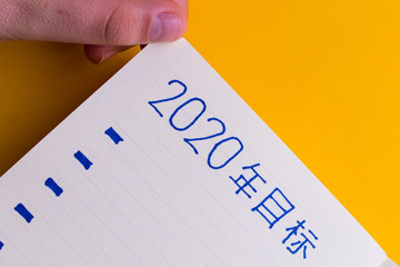 Woman's hands writing with Chinese characters in a diary the purposes for 2020