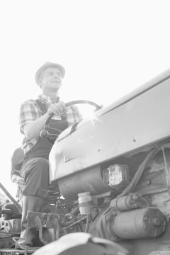 Black and white photo of mature farmer driving tractor in field