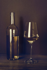 Botella de vino blanco y copa vista de frente