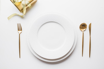 Elegant table setting with golden cutlery on white background. Top view.