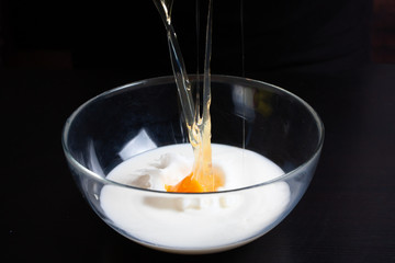 The cook breaks the egg into a glass bowl with milk to prepare a delicious meal. Pancake Recipe.