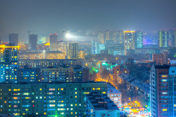 Top view of the city. Colorful street lighting of the night metropolis. Many high-rise buildings. Cold winter weather. Light haze. Novosibirsk, Siberia, Russia.