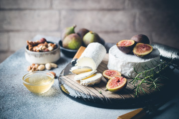 Fototapeta na wymiar Fresh goat brie cheese with truffle and white mold on cheese platter with figs and honey