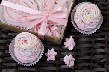 Aerial pink cherry marshmallows. In a gift box with a transparent cover. Near the marshmallows without packaging. Against the background of wicker vines.