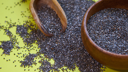Nutritious chia seeds on a yellow background. chia seeds in bowl and a spoon on kitchen table top...
