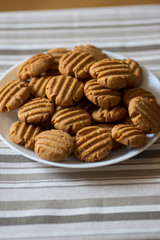 Pile of peanut butter biscuits on white plate, very tasty golden baked sweets, cookies served to eat
