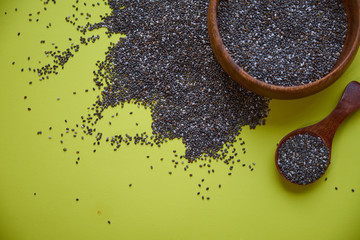 Nutritious chia seeds on a yellow background. chia seeds in bowl and a spoon on kitchen table top...