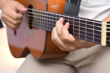 Fototapeta premium Hands of the guitarist, playing a melody on a wooden six-string acoustic guitar