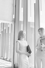 Black and white photo of businesswomen discussing plans before meeting in office hall