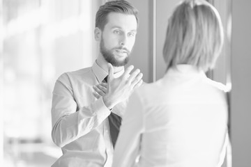 Fototapeta premium Black and white photo of businessman discussing plans with businesswoman before meeting