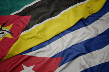 waving colorful flag of cuba and national flag of mozambique.
