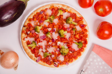 Pizza vegana con tomate, brócoli, cebolla y berenjena sobre fondo blanco.
