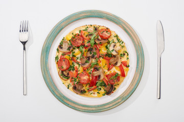 top view of plate with tasty omelet with tomatoes and mushrooms for breakfast on white table