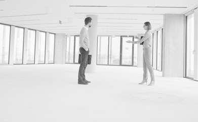 Black and white photo of businesswoman discussing and showing new office interior to businessman