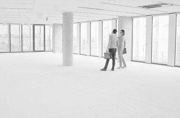 Black and white photo of businesswoman discussing and showing new office interior to businessman