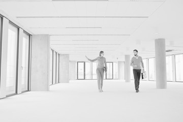 Black and white photo of businesswoman discussing and showing new office interior to businessman