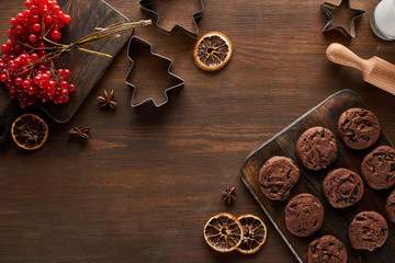 top view of chocolate cookies near Christmas dough molds, viburnum and spices on wooden table
