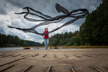 A girl of European appearance launches a large black kite. Flying kite.