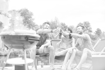 Woman preparing food in barbecue grill with friends on pier