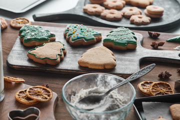 selective focus of baked Christmas cookies near ingredients on wooden table