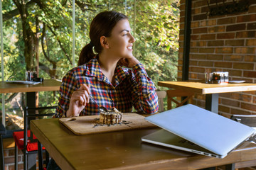 Attractive happy young woman sitting and eating dessert in cafe