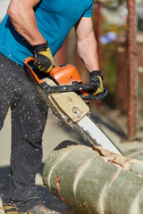 Anonymous man with chainsaw cutting logs