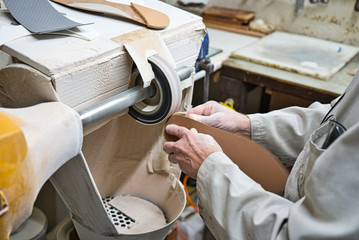 Professional craftsman of orthopedic insoles polishing, sanding and checking in his workshop the...