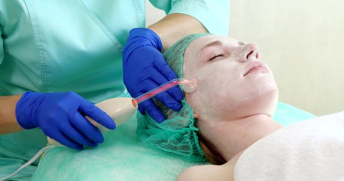 Woman getting electric darsonval facial therapy in salon