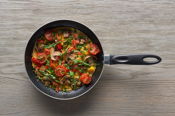 top view of delicious homemade omelet in frying pan on wooden table