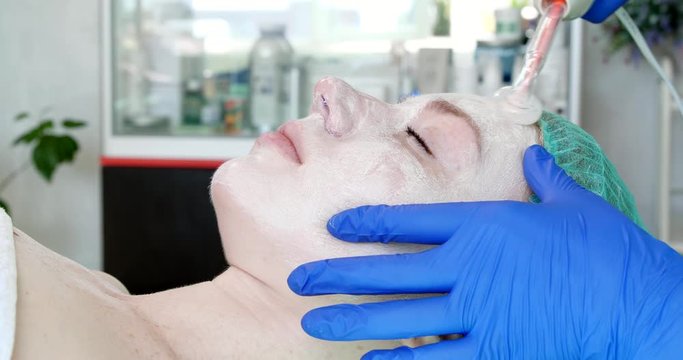 Woman getting electric darsonval facial therapy in salon