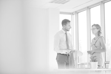 Fototapeta premium Businessman and businesswoman discussing at desk in new office