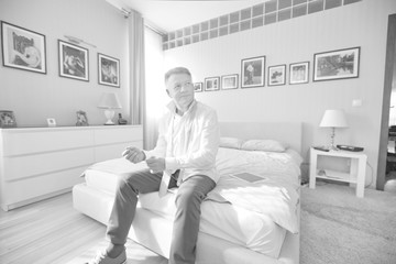 Full length view of confident businessman buttoning sleeve while sitting at home
