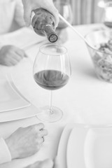 Man pouring red wine to womans wineglass