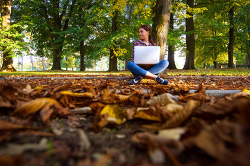 Happy hipster young woman working on laptop in the park