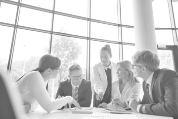 Business colleagues discussing while sitting at table in office lobby during meeting