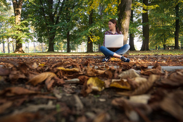 Happy hipster young woman working on laptop in the park