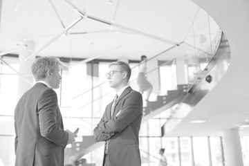 Black and white photo of Businessmen discussing while standing at new office