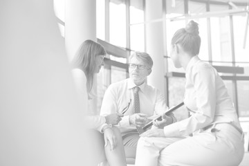 Black and white photo of Business colleagues planning strategy over document during meeting at office