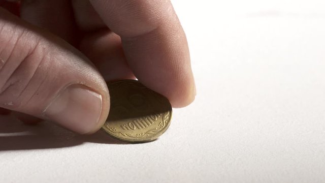 Hand taking 50 Ukrainian kopiyok coin from desk showing reverse side. 50 kopiyok equivalent to half a hryvnia. Currency of Ukraine.