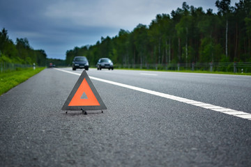 Warning triangle on a road in a green summer forest. Copy space