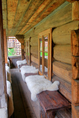 Bench with draped skins of sheep in front of the entrance to the traditional rural dwelling of...