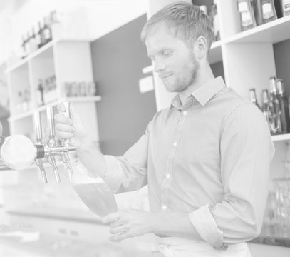 Black and white photo of Young waiter filling glass from beer tap at restaurant