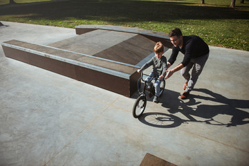 Obraz premium Father Learning his son to ride a bicycle