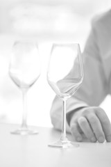 Black and white photo of wineglass on table against customer at restaurant