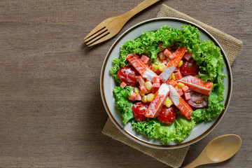 top view of crab stick salad in a ceramic dish on wooden table. homemade style healthy food concept.