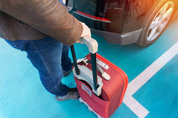 Man holding the suitcase near car