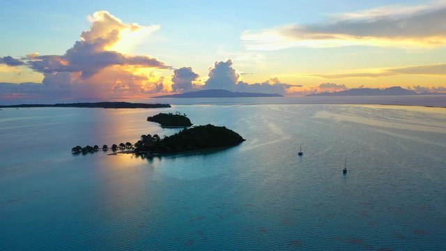 Aerial of an awesome sunset over the ocean, drone flying backwards - Bora Bora, French Polynesia